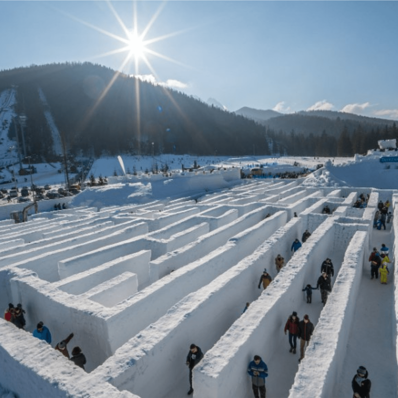 Большой снежный лабиринт с людьми в нем, расположенный в парке ледовых аттракционов в Закопане